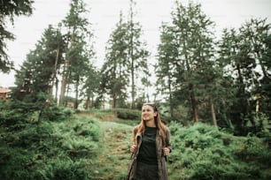 I love nature. Portrait of beautiful girl posing in forest during hike. She is looking away and smiling