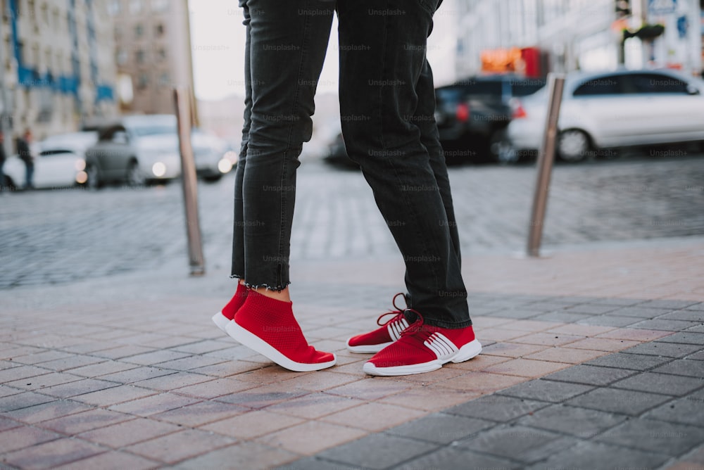 Close up picture of male and female legs in black jeans. Lady standing on tiptoe while hugging her boyfriend