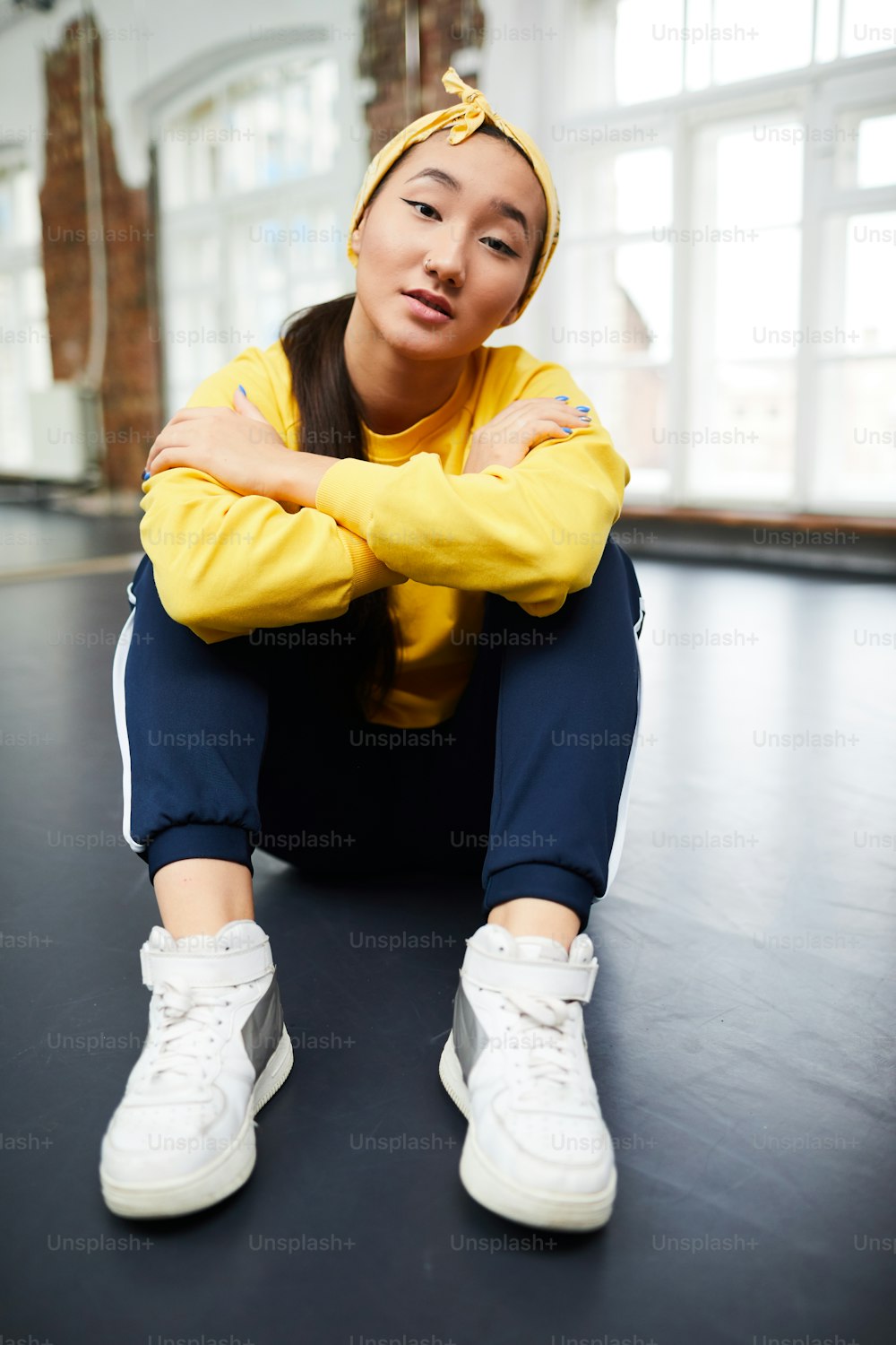 카메라 앞에서 현대 무용 스튜디오의 바닥에 앉아 있는 활동복을 입은 고요한 어린 소녀