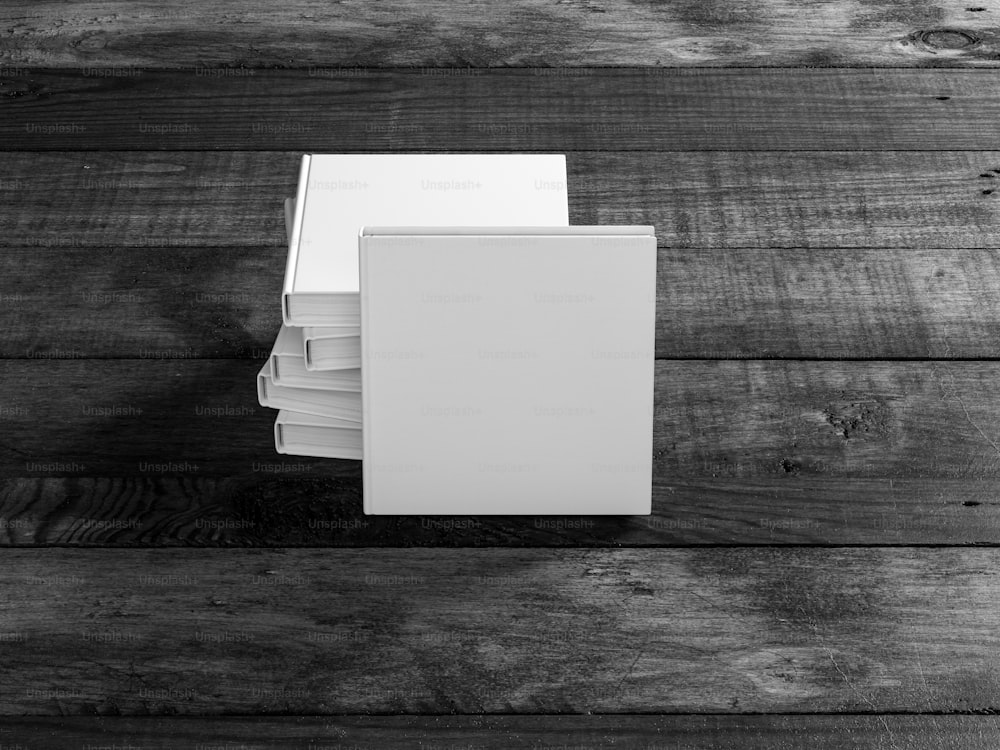 Maqueta de libro cuadrada blanca con tapa dura sobre mesa de madera. Renderizado 3D