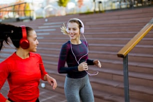 Two pretty young women running in urban area