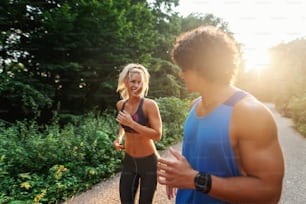 Cute sporty couple running in nature on the sunny summer day. Selective focus on woman.