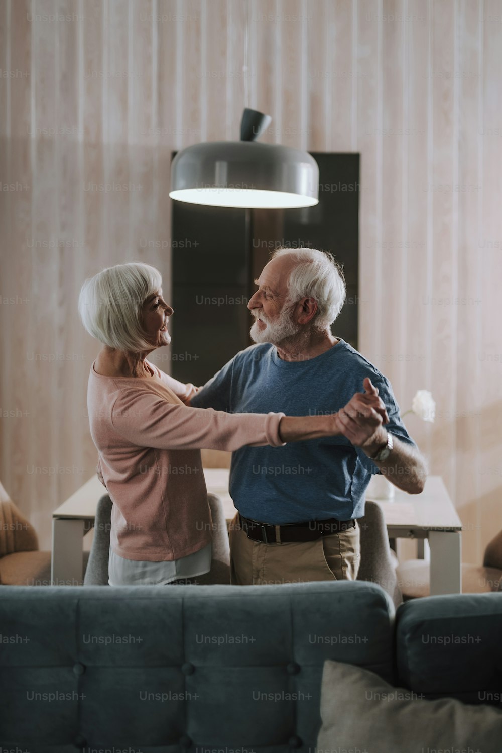 Love in any age. Waist up side on portrait of happy elder man and woman enjoying time together while dancing in living room at home