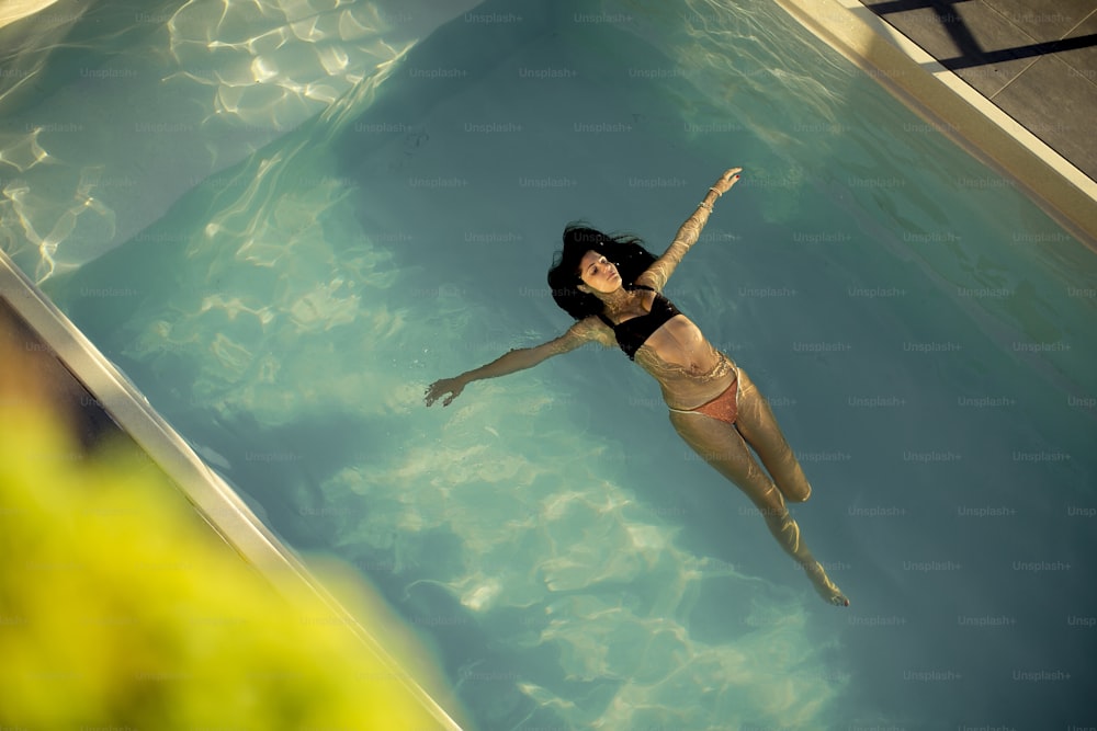 Vista aérea de la mujer nadadora flotando en la piscina en el día de verano
