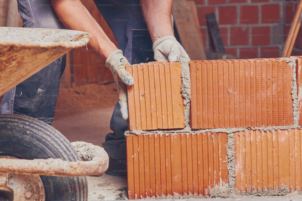 Real construction worker bricklaying the wall indoors.