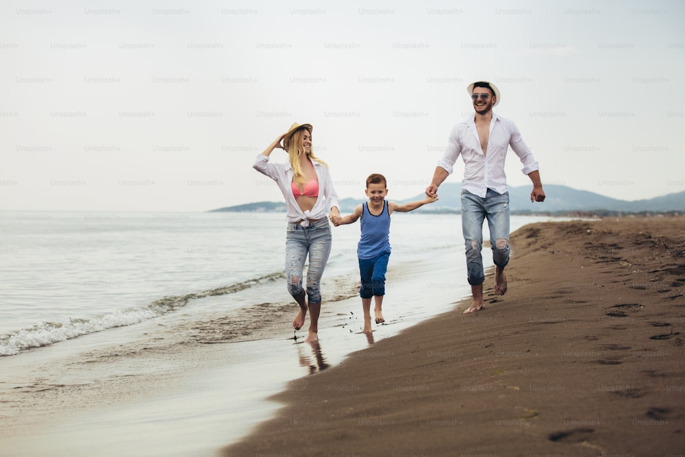 Pais caminhando ao longo da praia com a criança nas férias de verão