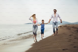 Parents Walking Along Beach With Child On Summer Vacation