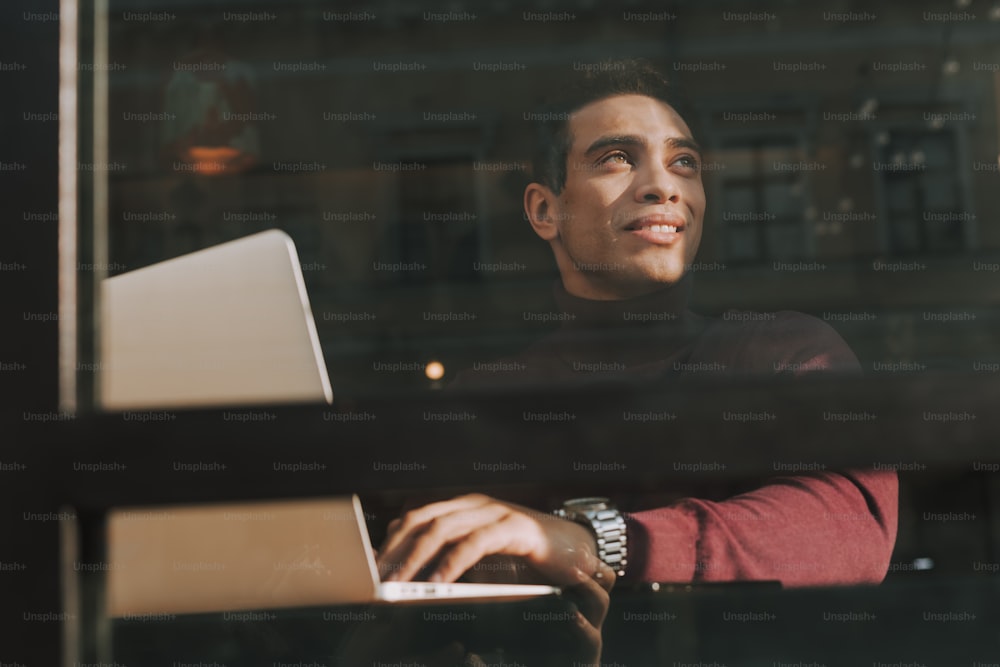 Low angle portrait of attractive elegant guy with notebook looking away and smiling
