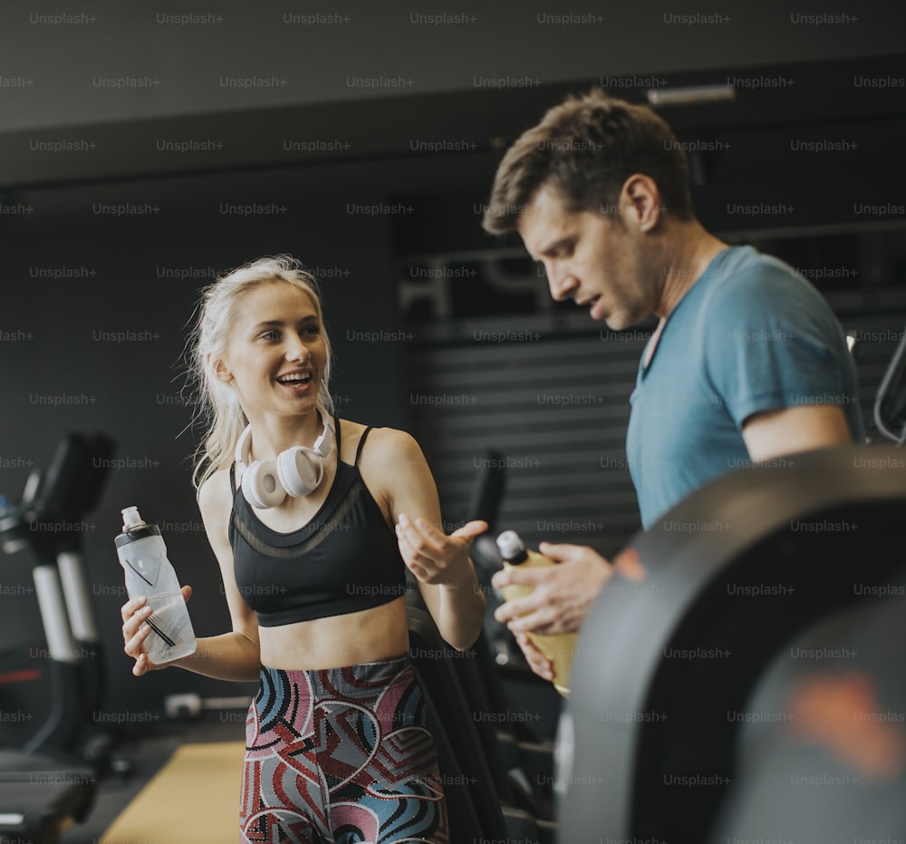 Young woman and personal male trainer rest in the gym after workout
