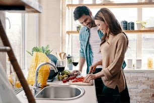 Beautiful young couple cooking dinner while standing in the kitchen at home