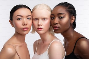 Between dark-eyed women. Blonde-haired young woman with bob cut standing between dark-eyed women