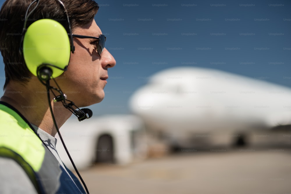 Great profile. Close up of serious man in sunglasses and headphones at airdrome. Copy space in right side