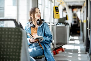 現代の路面電車で移動しながら本を読む若い女性、公共交通機関の幸せな乗客
