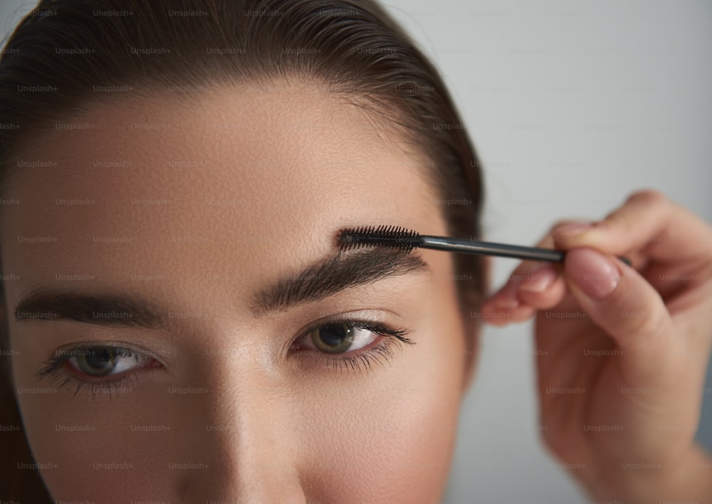 Primer plano de la cara femenina con cejas naturales. Están siendo cepillados después del tratamiento profesional