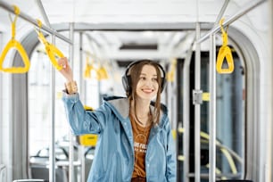 Mulher nova segurando a alça enquanto se move no bonde moderno. Passageiro feliz desfrutando de viagem no transporte público
