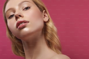 Natural beauty concept. Close up portrait of pretty young blonde lady with sensual glance confidently looking on camera. Isolated on pink with copy space on right