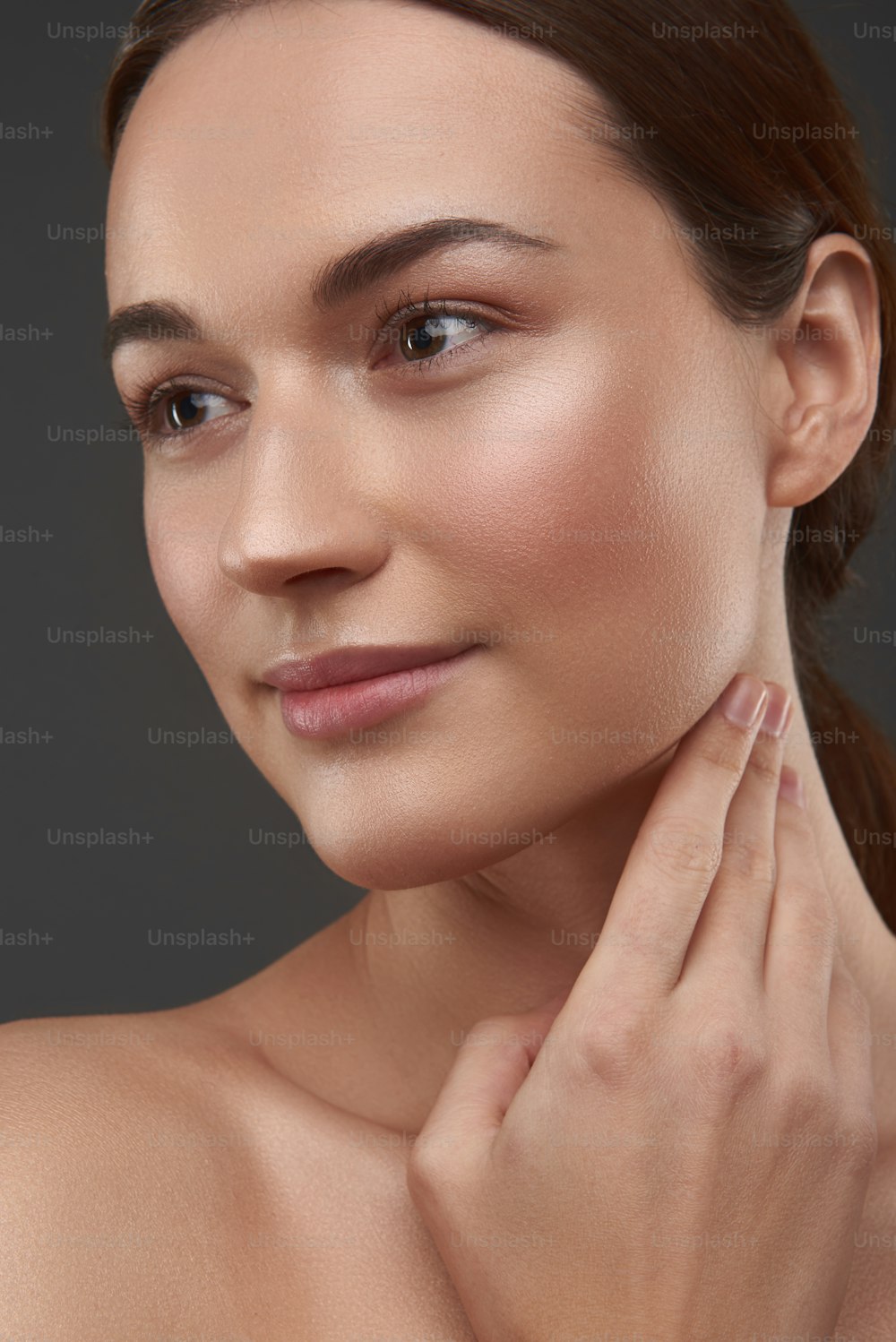 Close up portrait of charming lady with natural makeup looking away and smiling. Isolated on gray background