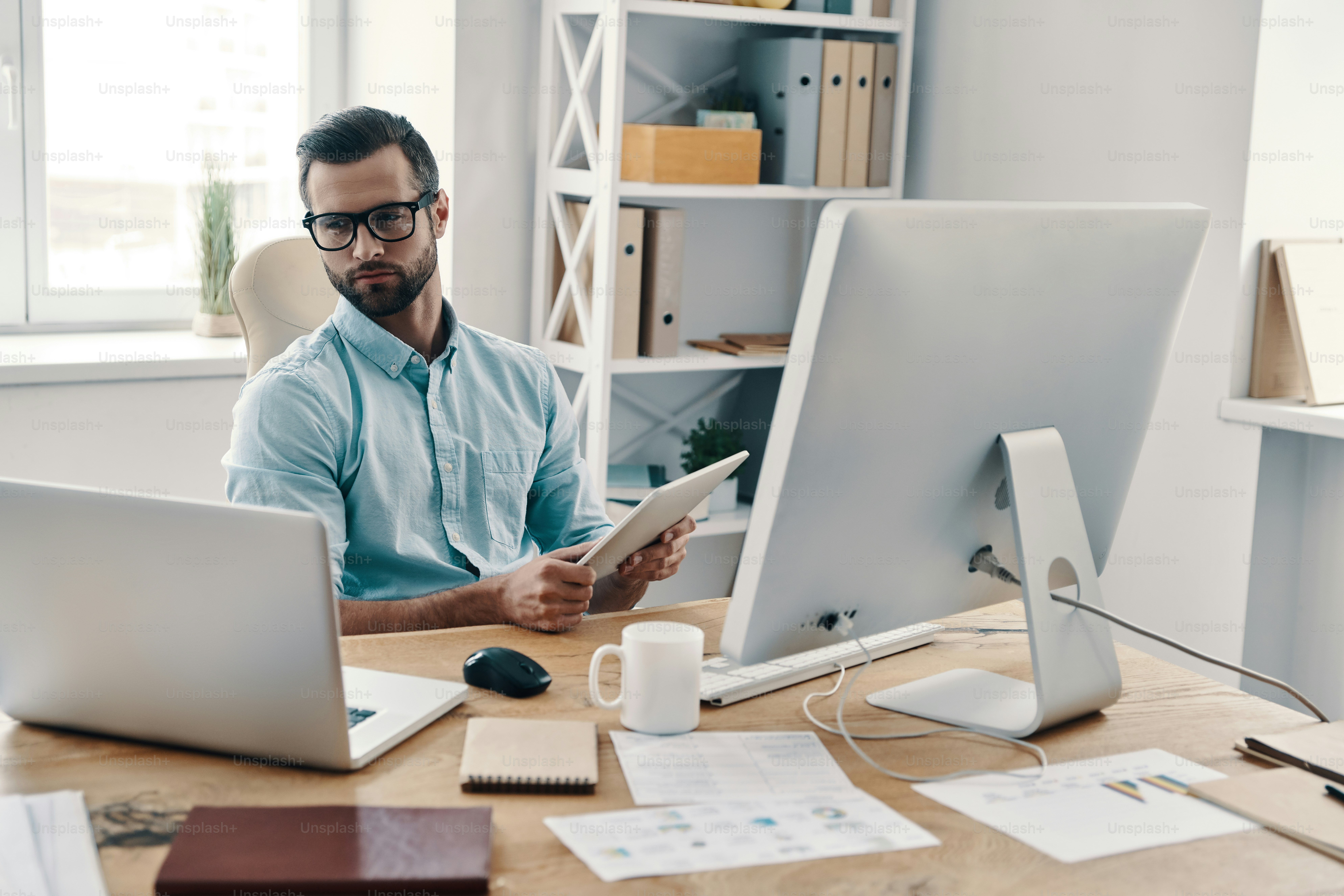 Young modern businessman working using digital tablet while sitting in the office