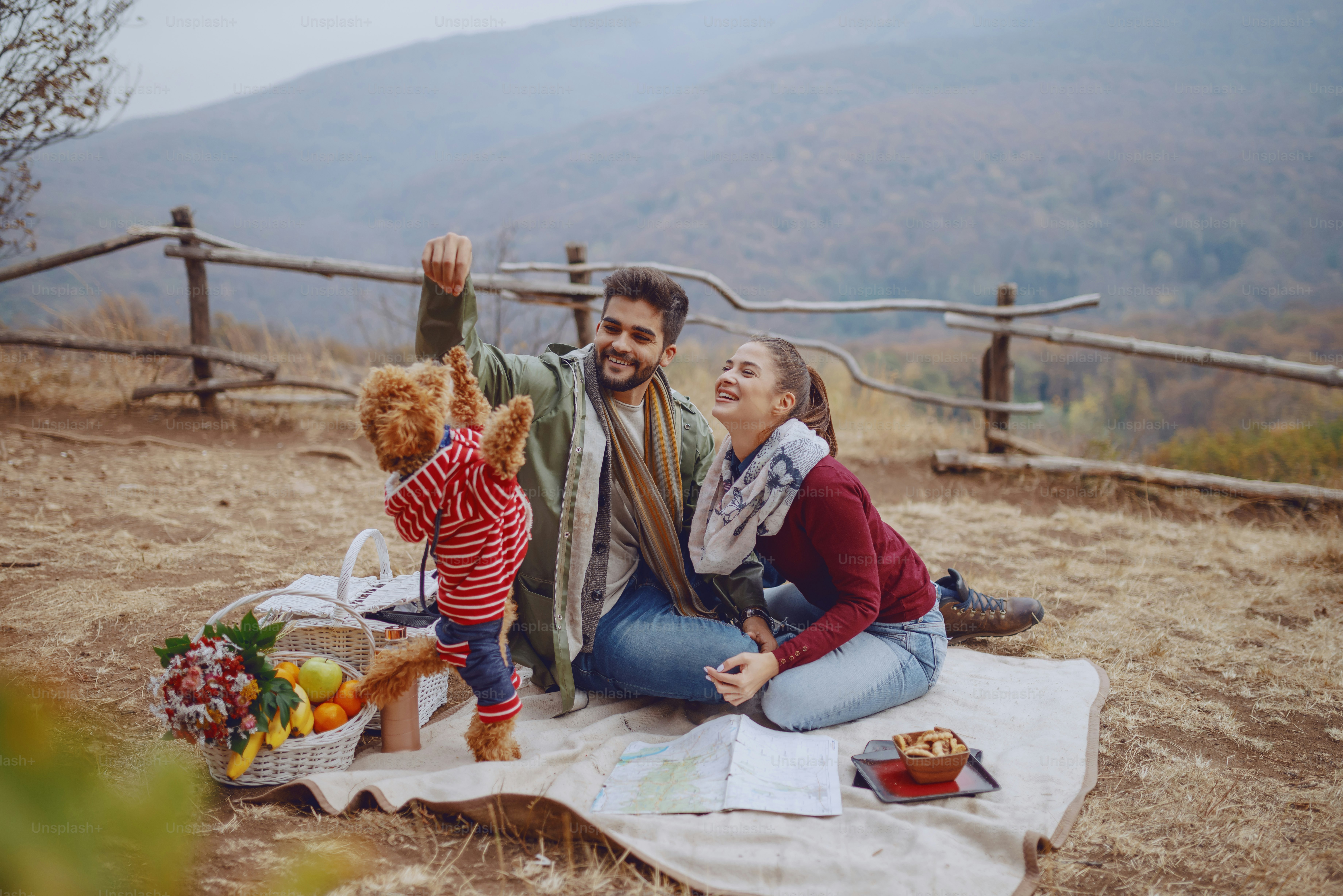 Attractive multicultural couple sitting on blanket and playing with ...