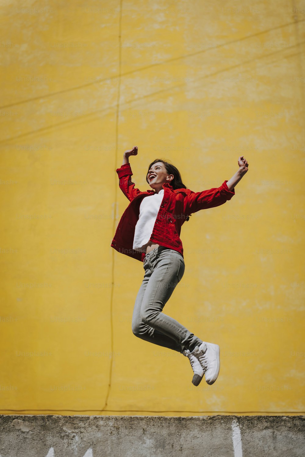 Urban lifestyle concept. Full length portrait of happy young hipster female jumping up on parapet