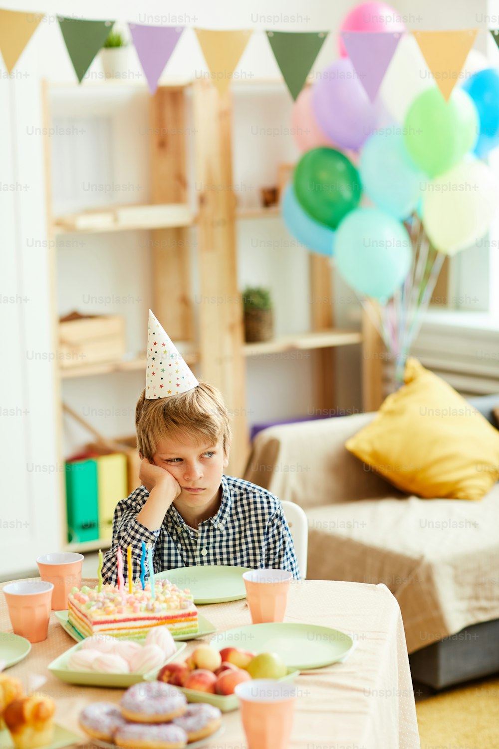 誕生日パーティー中に一人でテーブルに座っている悲しい男の子のポートレート、コピー用スペース