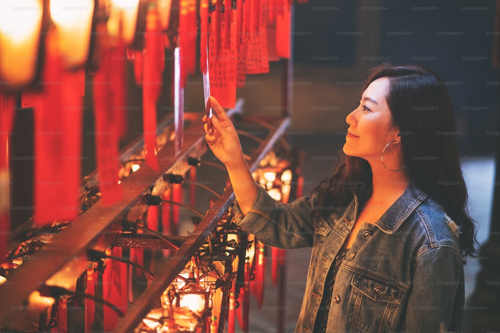 아름다운 아시아 여성은 중국 사원에서 빨간 램프와 소원을 보는 것을 즐겼습니다