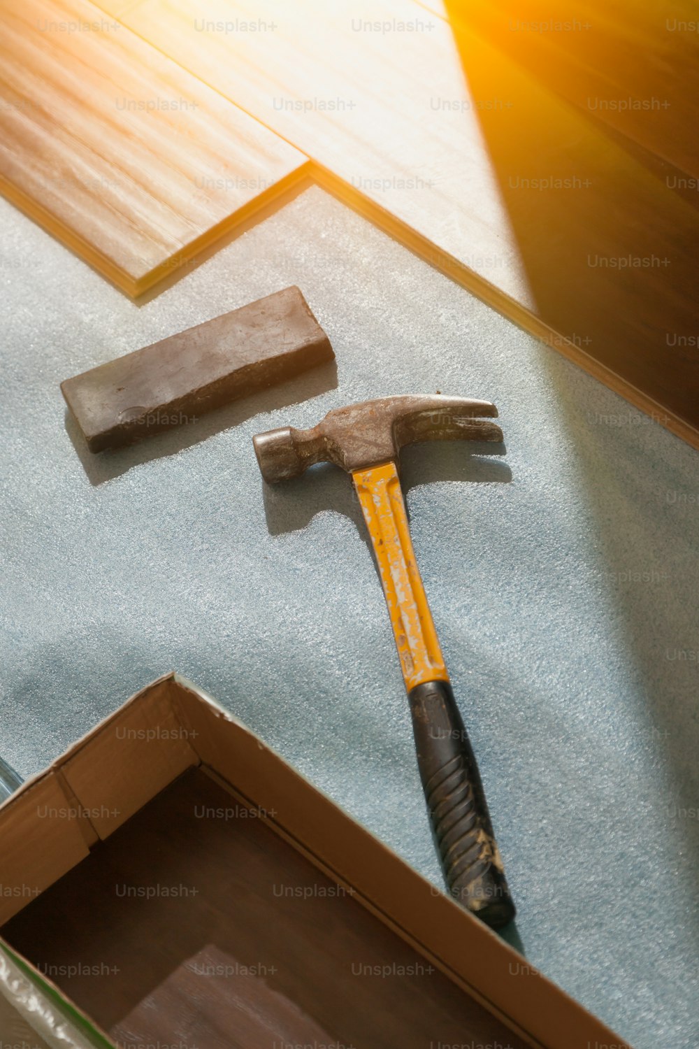 Hammer and Block with New Laminate Flooring Abstract.