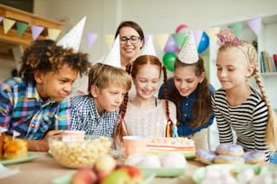 Multi ethnic group of kids looking at cake during fun Birthday party, copy space
