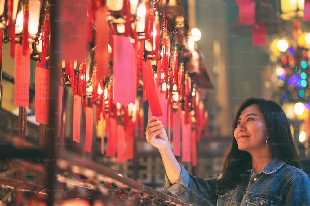 아름다운 아시아 여성은 중국 사원에서 빨간 램프와 소원을 보는 것을 즐겼습니다