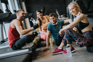 Group of young people in sportswear talking in a gym after a workout
