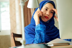 コンピュータの画面で�電子メールを読むときに電話で話す欲求不満のストレスを受けたイスラム教徒の女性