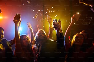 コンサートでお気に入りの歌手をサポートしながら、懐中電灯をつけてガジェットを振る陽気なのんきな若者の群衆