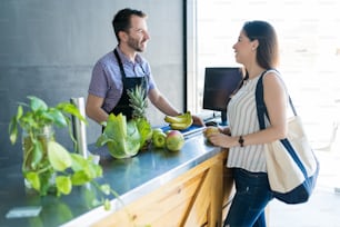 Mid adult grocery owner talking with female customer in supermarket