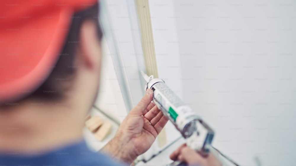 Arbeiter mit Silikon für Wände und Türrahmen im Haus - Renovierungskorrekturen.