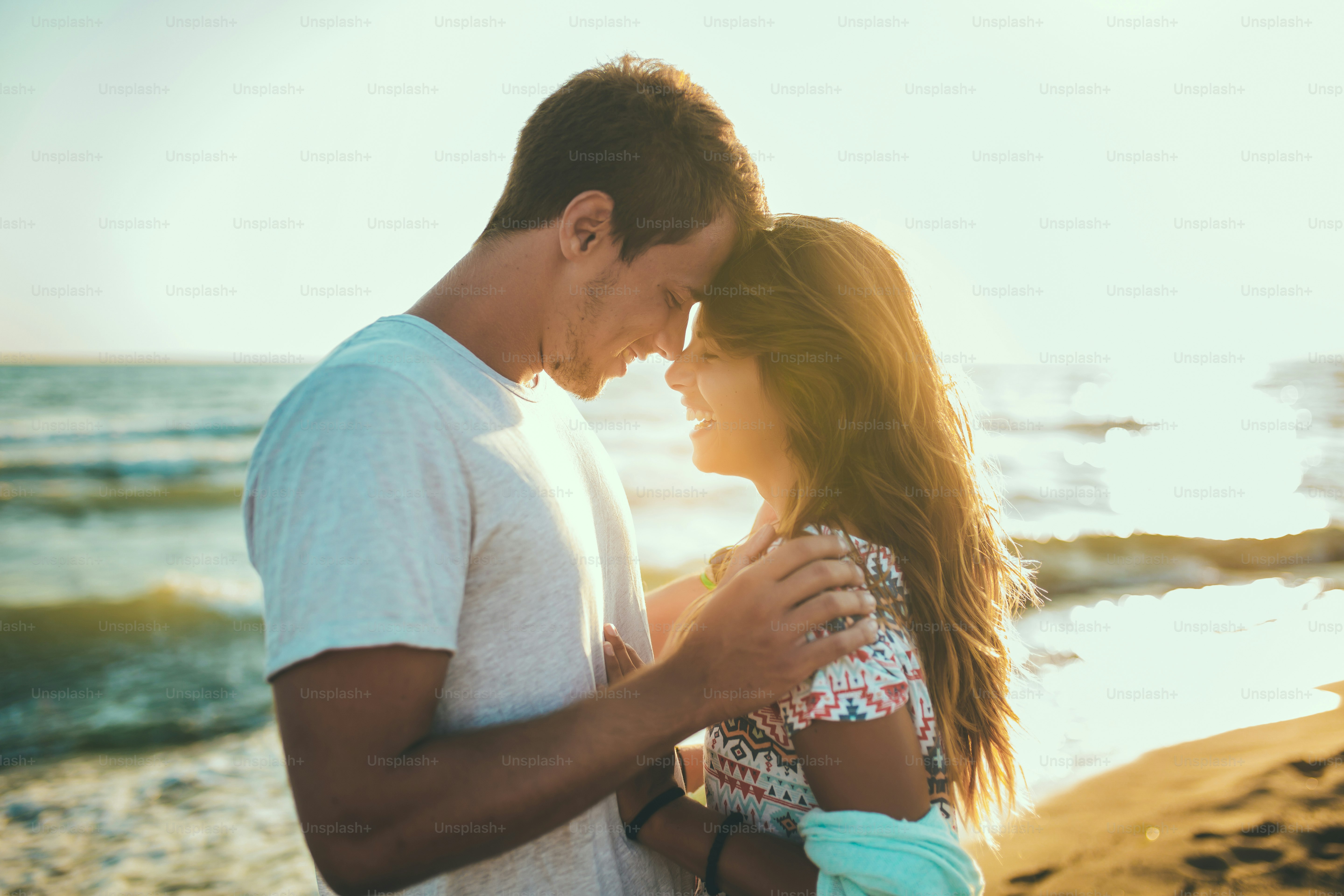 夏休みを楽しむロマンチックな若い夫婦。ビーチでガールフレンドを持つハンサムな若い男。