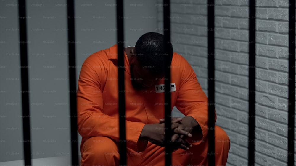 Prisionero afroamericano pensativo esperando visitas, cumpliendo cadena perpetua