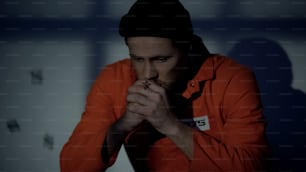 Homem preso europeu segurando cruz de prata e orando na cela sentindo-se culpado