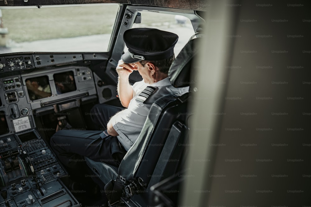 Piloto masculino com dor de cabeça está sentado na cabine stock photo. Conceito de saúde