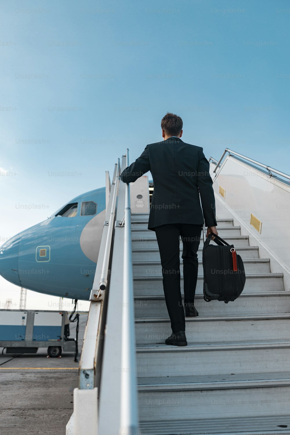 スーツを着た成人男性とバッグが旅客機で旅行する写真素材。航空路コンセプト