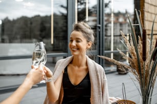 Young woman drinking wine, while relaxing on the terrace with hot vat at the luxury SPA