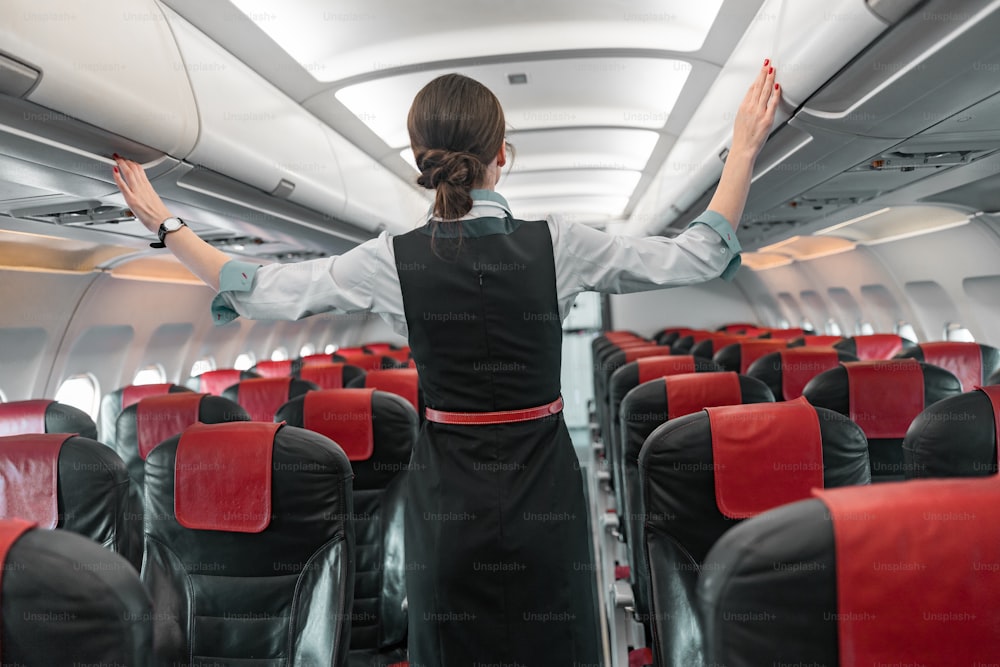 Female flight attendant doing her job in airplane stock photo. Airways concept