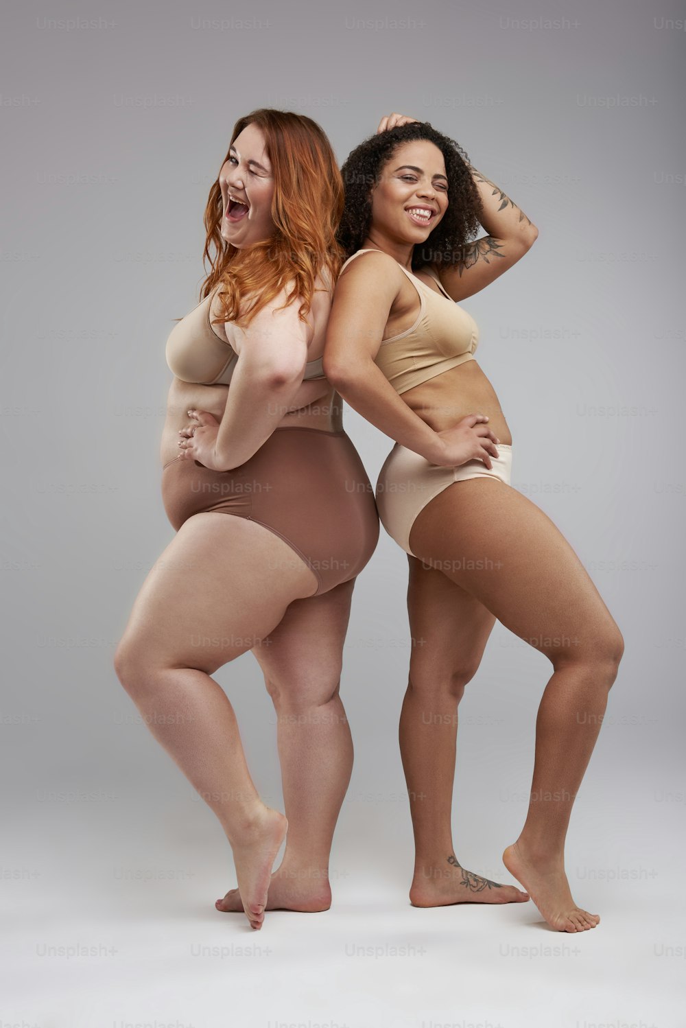 Caucasian woman and Afro American lady laughing together. Overweight concept