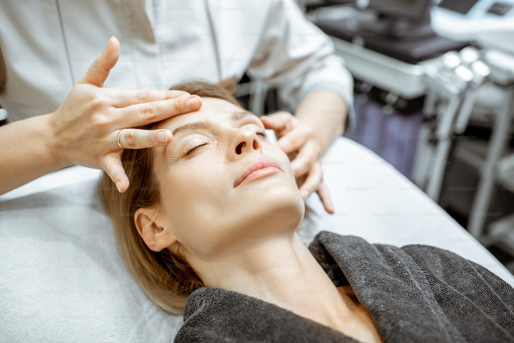 Mujer haciendo masaje facial en el salón de belleza. Concepto de una terapia de drenaje linfático