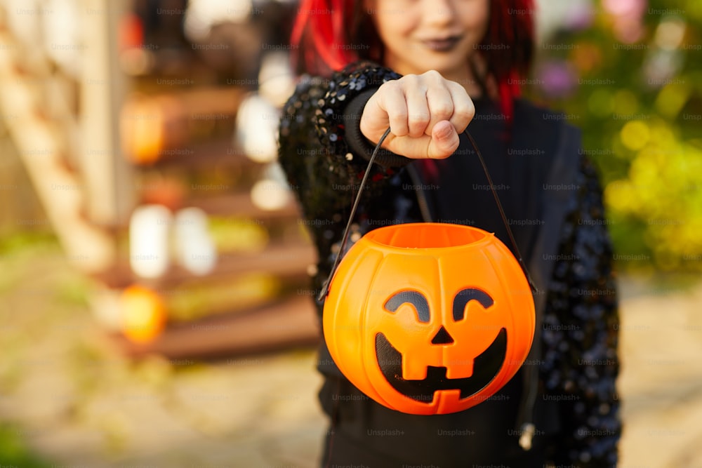 Nahaufnahme eines nicht wiederzuerkennenden kleinen Mädchens, das Halloween-Kostüm trägt und Kürbiskorb in der Trick or Treat-Saison hält, Kopierraum