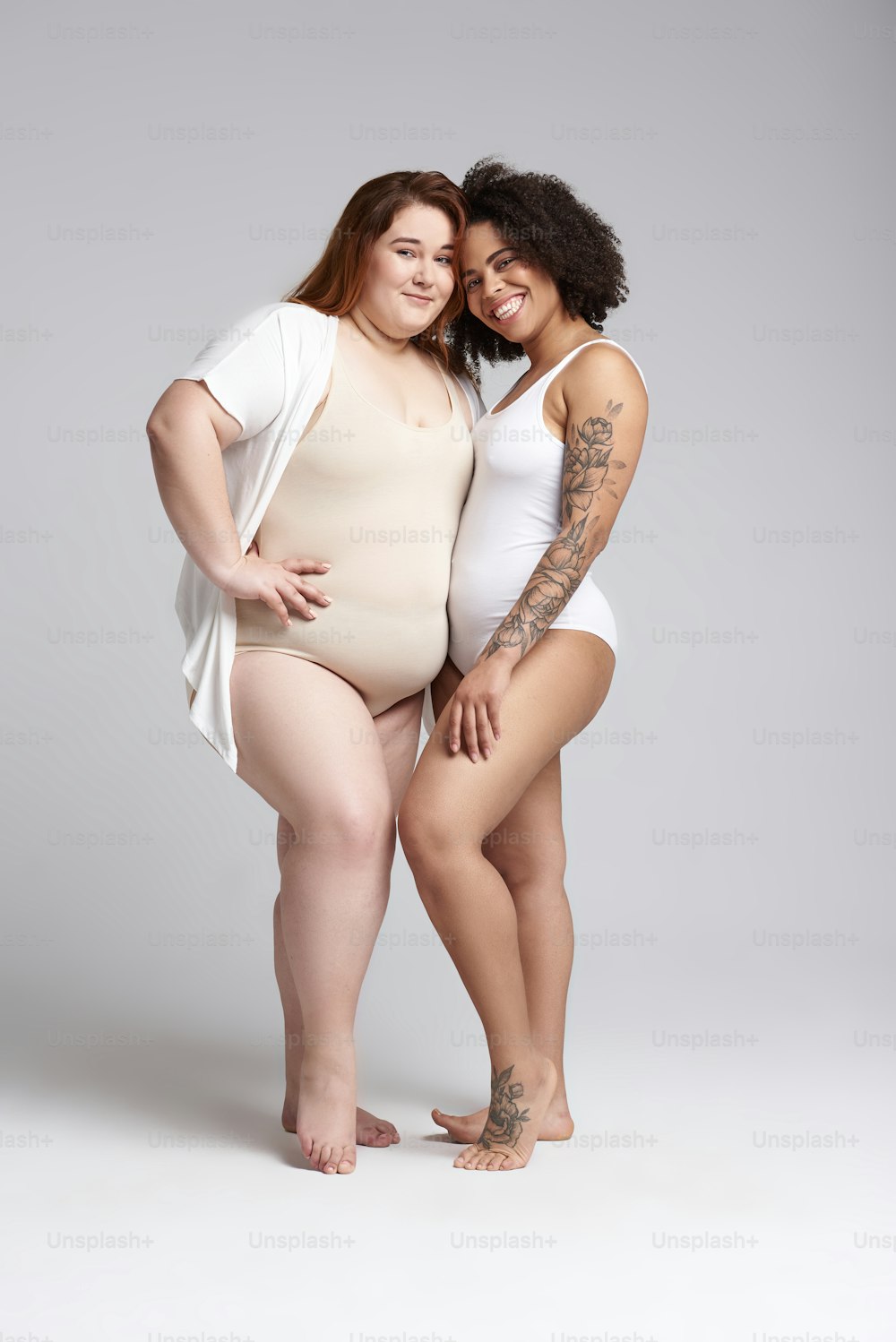 Caucasian woman and Afro American lady smiling and posing for camera. Overweight concept