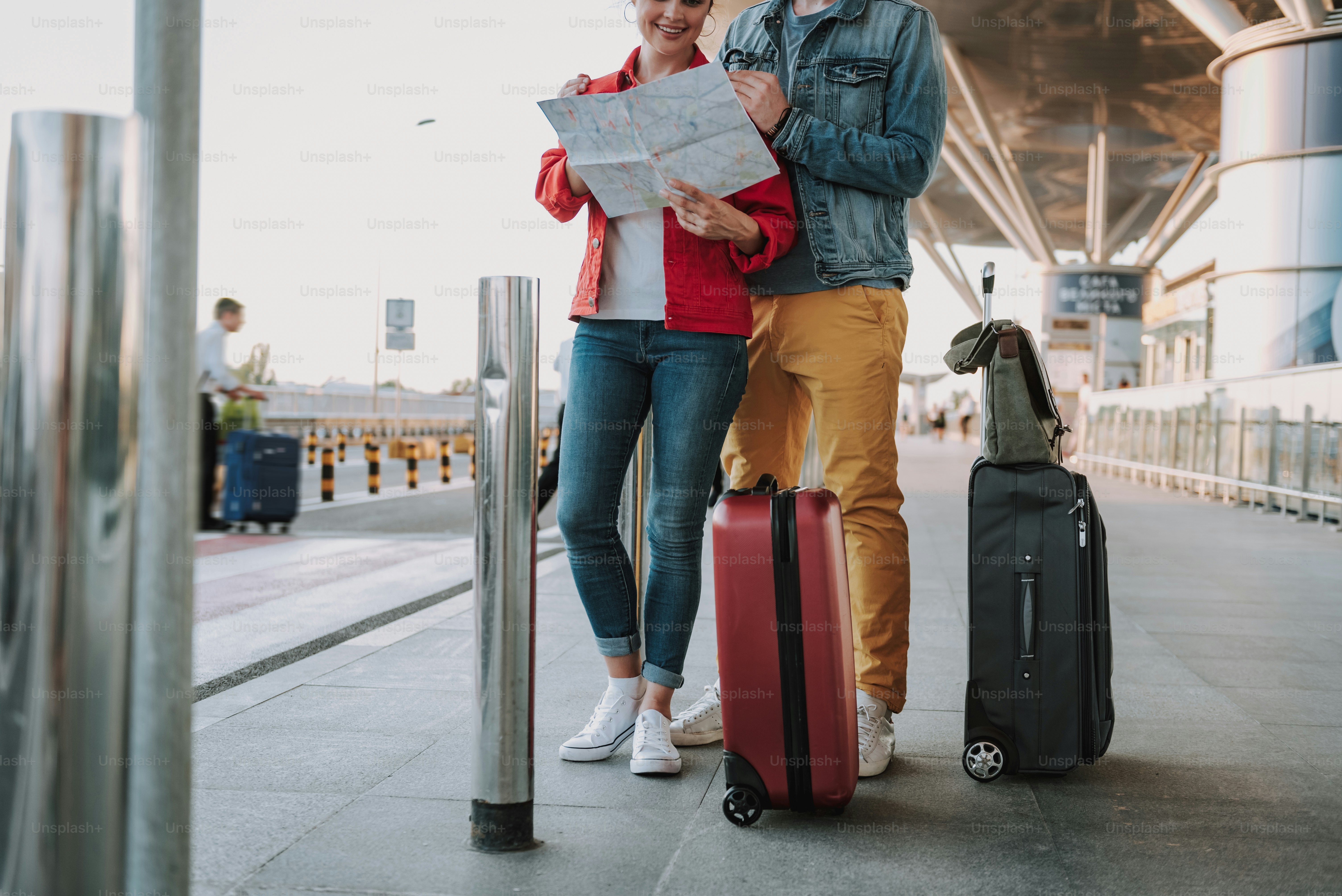 Cropped portrait of gentleman in denim jacket hugging his charming girlfriend from behind while she searching route on map