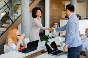Young businesspeople shaking hands in the office when finishing successful meeting