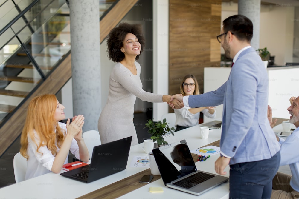 Jóvenes empresarios dándose la mano en la oficina al terminar una reunión exitosa