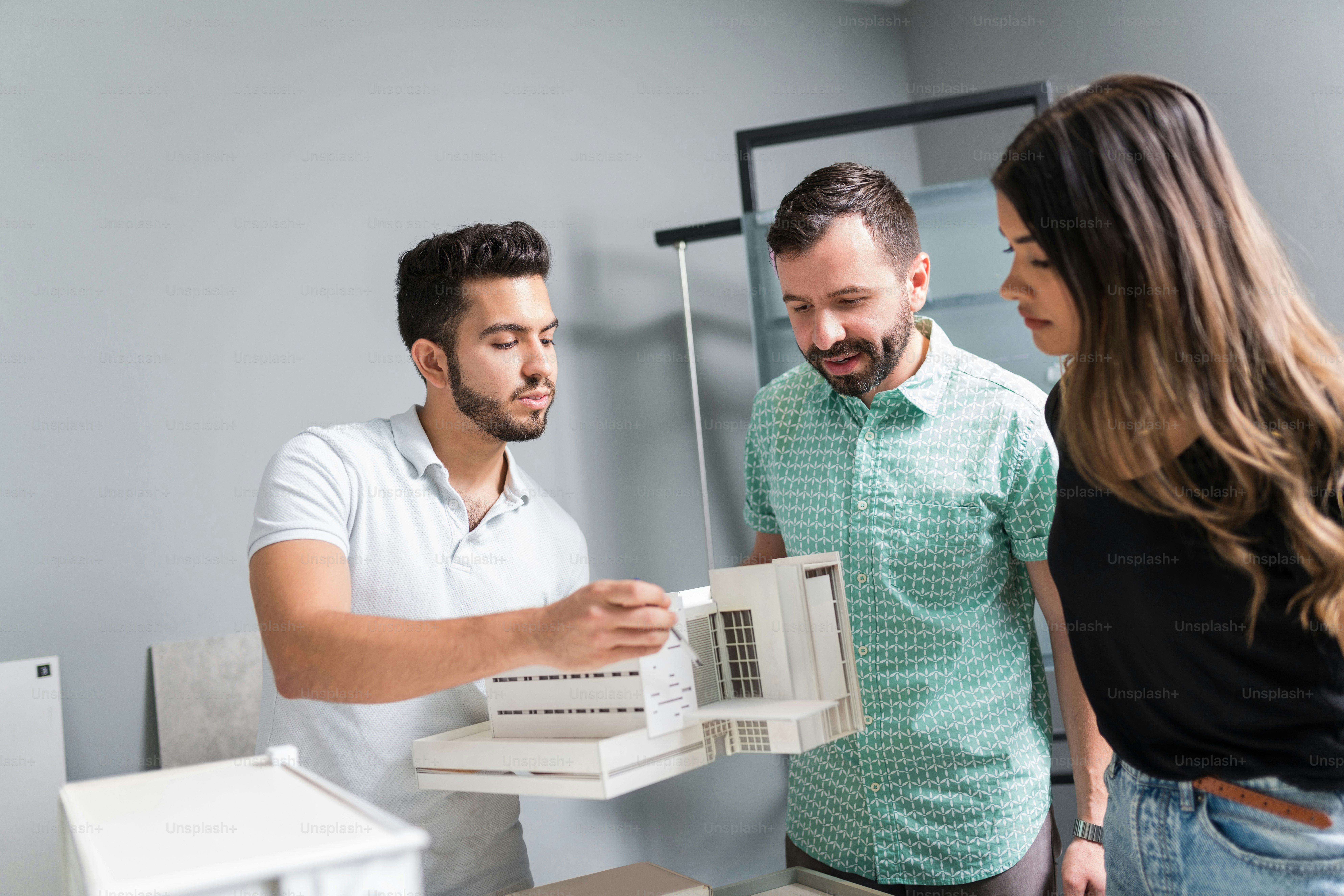 Young engineer explaining architectural model to business colleagues in