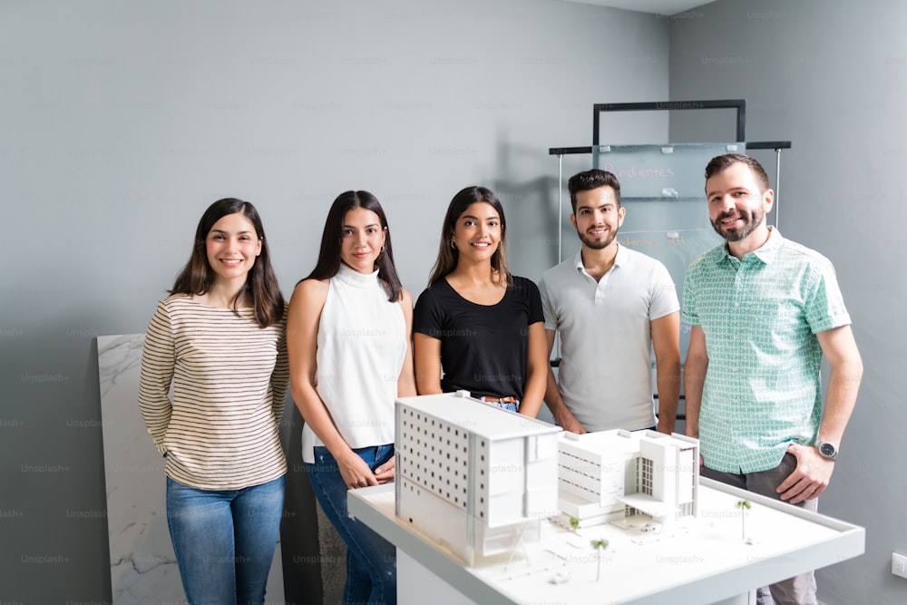 Confident male and female engineers standing with new architectural project at workplace